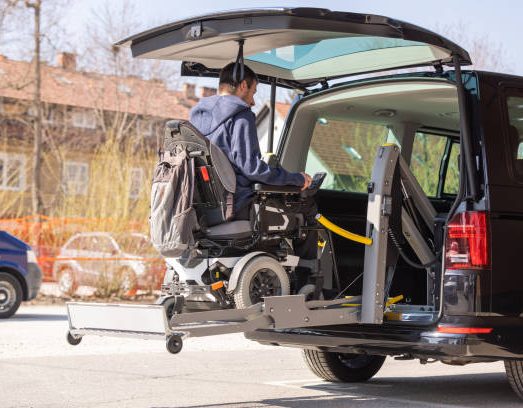 Een persoon in een rolstoel wordt met een lift in een bus getransporteerd.