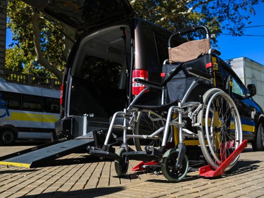 Een rolstoel staat klaar bij een bestelbus met een oprijplaat.